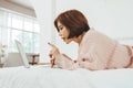 Asian Korean woman lying on the bed using laptop Royalty Free Stock Photo