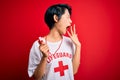 Young beautiful asian lifeguard girl wearing t-shirt with red cross using whistle bored yawning tired covering mouth with hand