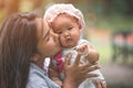 Young beautiful Asian mother holding and kissing her daughter outdoor Royalty Free Stock Photo