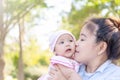 Young beautiful Asian mother kissing her little baby 4 months girl. Family; mother and daughter having a free time relaxing in Royalty Free Stock Photo