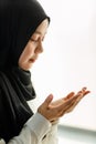 Young and beautiful Asian Muslim woman in black veil sitting on floor and praying with respect and calm manner Royalty Free Stock Photo