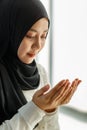 Young and beautiful Asian Muslim woman in black veil sitting on floor and praying with respect and calm manner Royalty Free Stock Photo