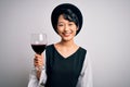 Young beautiful asian sommelier girl drinking glass of red wine over isolated white background with a happy face standing and