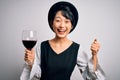 Young beautiful asian sommelier girl drinking glass of red wine over isolated white background screaming proud and celebrating