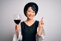 Young beautiful asian sommelier girl drinking glass of red wine over isolated white background surprised with an idea or question