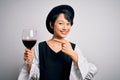 Young beautiful asian sommelier girl drinking glass of red wine over isolated white background very happy pointing with hand and