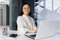 Young beautiful asian successful woman working inside modern office building, using laptop at workplace, businesswoman Royalty Free Stock Photo