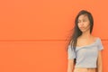 Young beautiful Asian teenage girl against orange wall Royalty Free Stock Photo