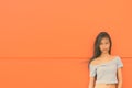 Young beautiful Asian teenage girl against orange wall Royalty Free Stock Photo