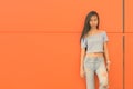 Young beautiful Asian teenage girl against orange wall Royalty Free Stock Photo