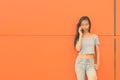 Young beautiful Asian teenage girl against orange wall Royalty Free Stock Photo