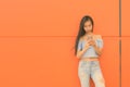 Young beautiful Asian teenage girl against orange wall Royalty Free Stock Photo