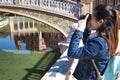 Young and beautiful asian tourist taking photos of monuments with reflex camera leaning on a railing during her vacation trip Royalty Free Stock Photo