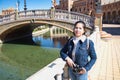 Young and beautiful asian tourist taking photos with reflex camera in her hand leaning on a railing during her vacation trip Royalty Free Stock Photo