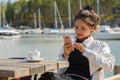 Young beautiful Asian tourist woman using phone at restaurant by the pier Royalty Free Stock Photo