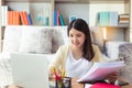 Young beautiful asian university student girl study and learning online of lessons on laptop computer and holding documents at Royalty Free Stock Photo