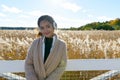 Young beautiful Asian woman against scenic view of autumn bulrush field