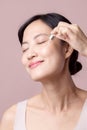 Beautiful young asian woman applying serum facial oil on natural mack up face skin. Portrait health wellness clean skincare female Royalty Free Stock Photo