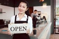 Young beautiful Asian woman barista holding open sign broad at restaurant and coffee shop for telling customers that shop is ready Royalty Free Stock Photo