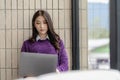 Young beautiful asian woman in casual clothes sits in chair using laptop computer Royalty Free Stock Photo