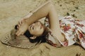 A young beautiful Asian woman dazzled by the light while lying on the beach sand