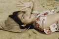 A young beautiful Asian woman dazzled by the light while lying on the beach sand