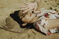 A young beautiful Asian woman dazzled by the light while lying on the beach sand