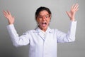 Young beautiful Asian woman doctor acting crazy while wearing novelty glasses Royalty Free Stock Photo