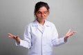 Young beautiful Asian woman doctor acting crazy while wearing novelty glasses