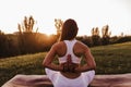 young beautiful asian woman doing yoga in a park at sunset. Yoga and healthy lifestyle concept. Back view Royalty Free Stock Photo