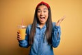 Young beautiful asian woman drinking healthy glass of orange juice over yellow background very happy and excited, winner Royalty Free Stock Photo