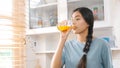 Young beautiful asian woman drinking orange juice while standing by window in kitchen background, peolpe and healthy lifestyles Royalty Free Stock Photo