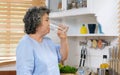 Young beautiful asian woman drinking water while standing by window in kitchen background, people and healthy lifestyles Royalty Free Stock Photo