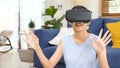 Young beautiful asian woman exciting in VR headset looking up and trying to touch objects in virtual reality at home living room, Royalty Free Stock Photo