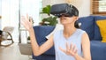 Young beautiful asian woman exciting in VR headset looking up and trying to touch objects in virtual reality at home living room, Royalty Free Stock Photo