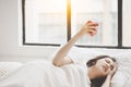 Young beautiful asian woman hate waking up early in the morning Young woman pressing snooze button on early morning alarm clock Royalty Free Stock Photo