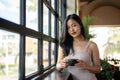 Young beautiful Asian woman having a coffee break while leaning against the windows Royalty Free Stock Photo