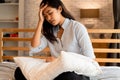 Young beautiful Asian woman having a headache while lying on bed, feeling sad and stressed at home. Disappointed and Royalty Free Stock Photo