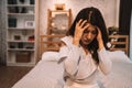 Young beautiful Asian woman having a headache while lying on bed, feeling sad and stressed at home. Disappointed and Royalty Free Stock Photo