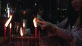 Beautiful asian woman light the incense from red candle to pray the buddha , chinese gods and pay respect to ancestor