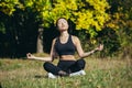 Young beautiful asian woman performs fitness yoga exercises, sitting in lotus position on the grass and meditating in the park Royalty Free Stock Photo