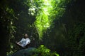 Young beautiful Asian woman practicing Yoga posing sitting in lotus position meditating over a stone in a stunning natural landsca Royalty Free Stock Photo