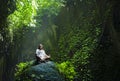 Young beautiful Asian woman practicing Yoga posing sitting in lotus position meditating over a stone in a stunning natural landsca Royalty Free Stock Photo