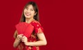 Young beautiful asian woman in red dress holding and showing red envelopes of Chinese New Year bunus and gift on red background Royalty Free Stock Photo