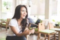 Young beautiful asian woman in a restaurant, holding cellphone Royalty Free Stock Photo