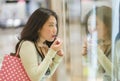 Young beautiful Asian woman shopping at modern mall - happy and attractive Chinese girl holding shopping bags using fashion store Royalty Free Stock Photo