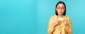 Young beautiful asian woman showing credit card, smiling, choosing bank, standing over blue background