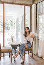 Young beautiful Asian woman sitting alone inside an old house  by the large window waiting for her friends Royalty Free Stock Photo