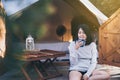 Young beautiful asian woman sitting at tent and drinking coffee in the morning,Enjoys of resting time,Happy and smiling Royalty Free Stock Photo