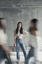 Young beautiful Asian woman standing casually posing for the camera at an indoor rustic place while people walking blurry in front